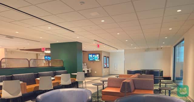 Armchairs and booths in the seating area of the Escape Lounge at Tulsa International Airport.